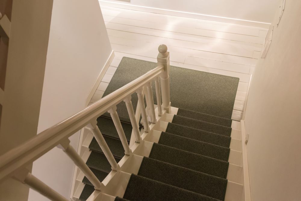 Green stair carpet on white staircase